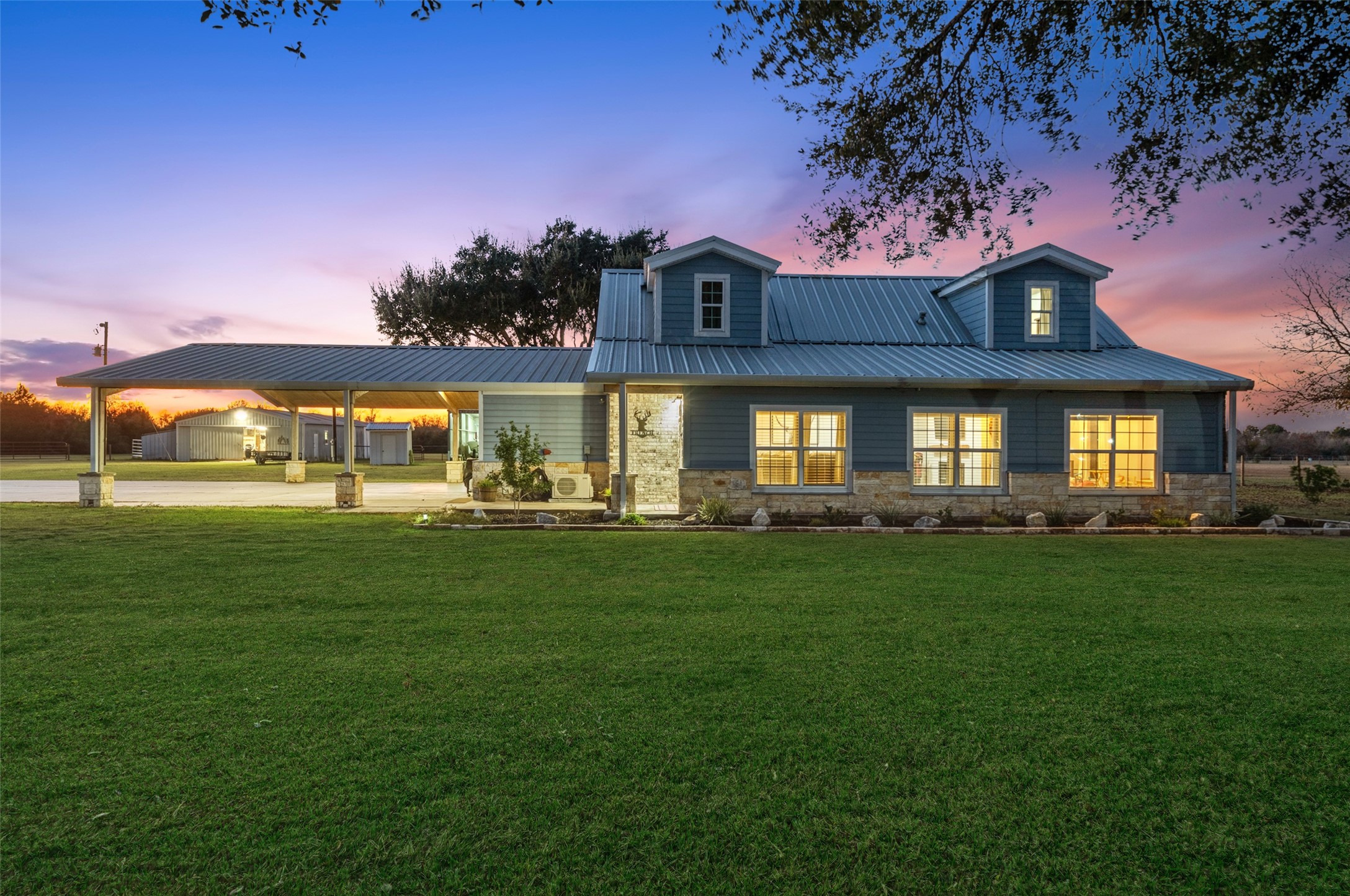 Evening view showcases the home’s welcoming exterior, enclosed front porch, and durable metal roof set against a peaceful rural backdrop.