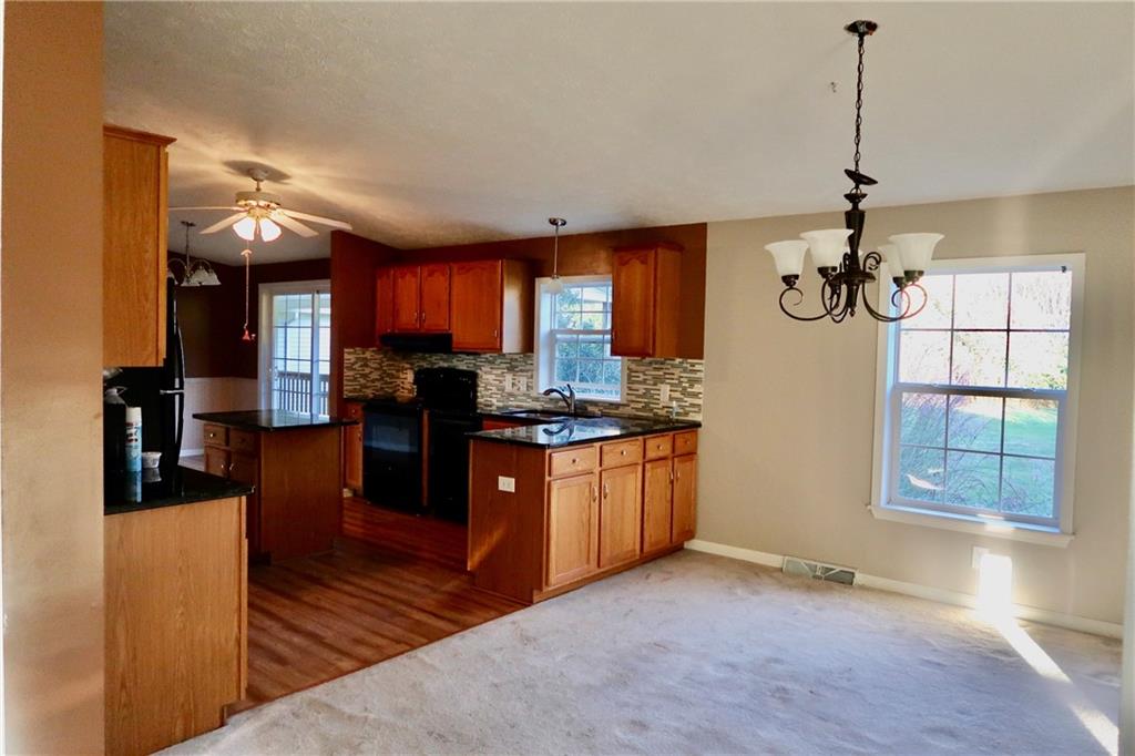128 Airport Road Mercer, PA 16137 - Photo 17 of 36 a kitchen with stainless steel appliances granite countertop a refrigerator a sink dishwasher a stove and a dining table with wooden floor