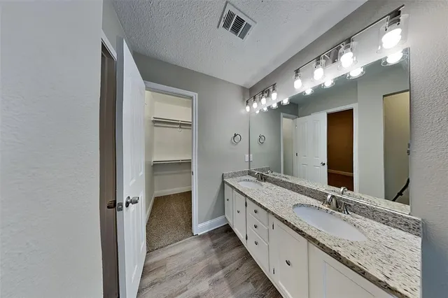 a bathroom with a granite countertop double vanity sink and a mirror