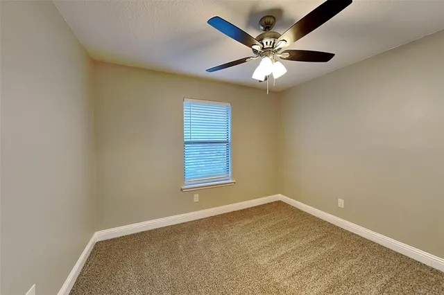 an empty room with a window and a ceiling fan