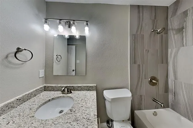a bathroom with a granite countertop sink a toilet and shower