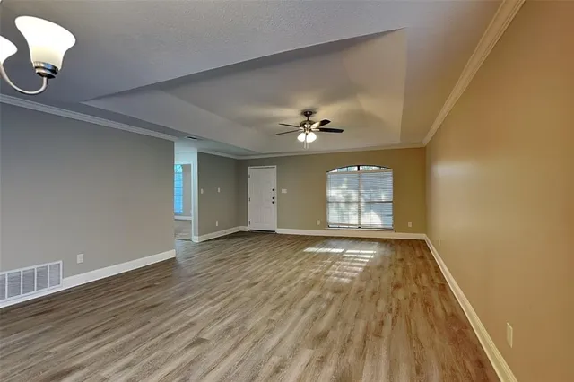 a view of an empty room with window and wooden floor