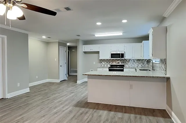 a large kitchen with stainless steel appliances granite countertop a stove a sink and white cabinets