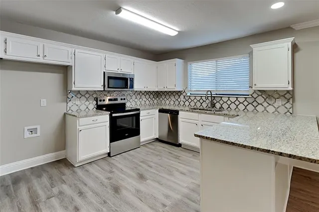 a kitchen with granite countertop a stove sink and cabinets
