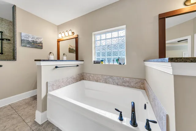 a bathroom with a tub sink and mirror