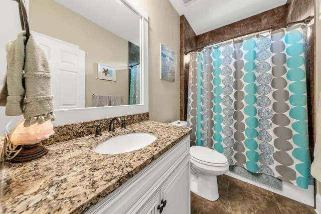 a bathroom with a granite countertop sink a toilet and a shower curtain