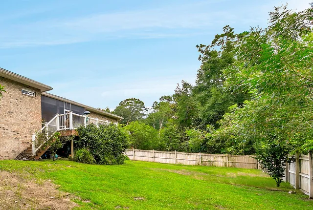 a view of a house with a big yard potted plants and large tree