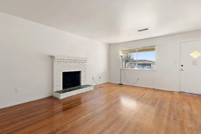 an empty room with wooden floor and fireplace