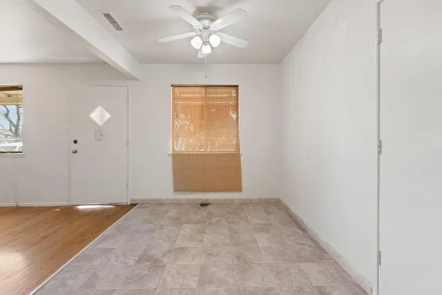 an empty room with windows and fan