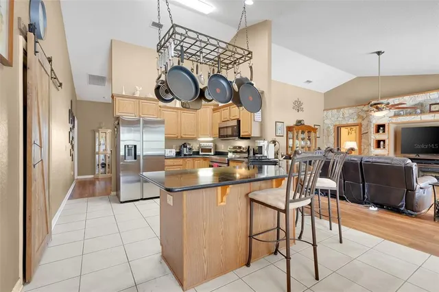a kitchen with stainless steel appliances kitchen island granite countertop a table and chairs in it