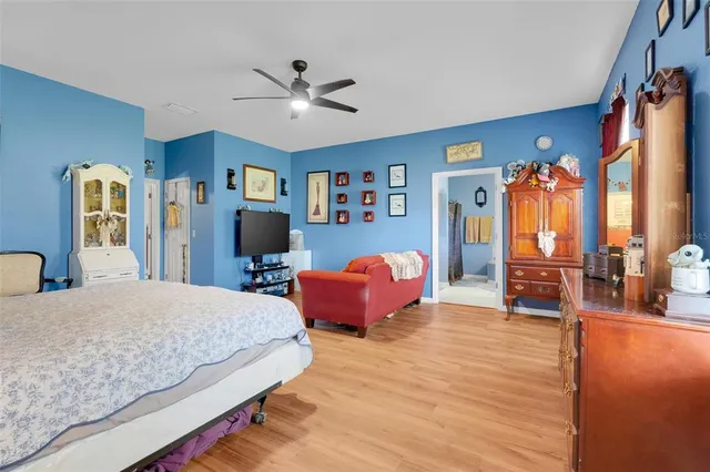 a bedroom with a bed and dresser with wooden floor