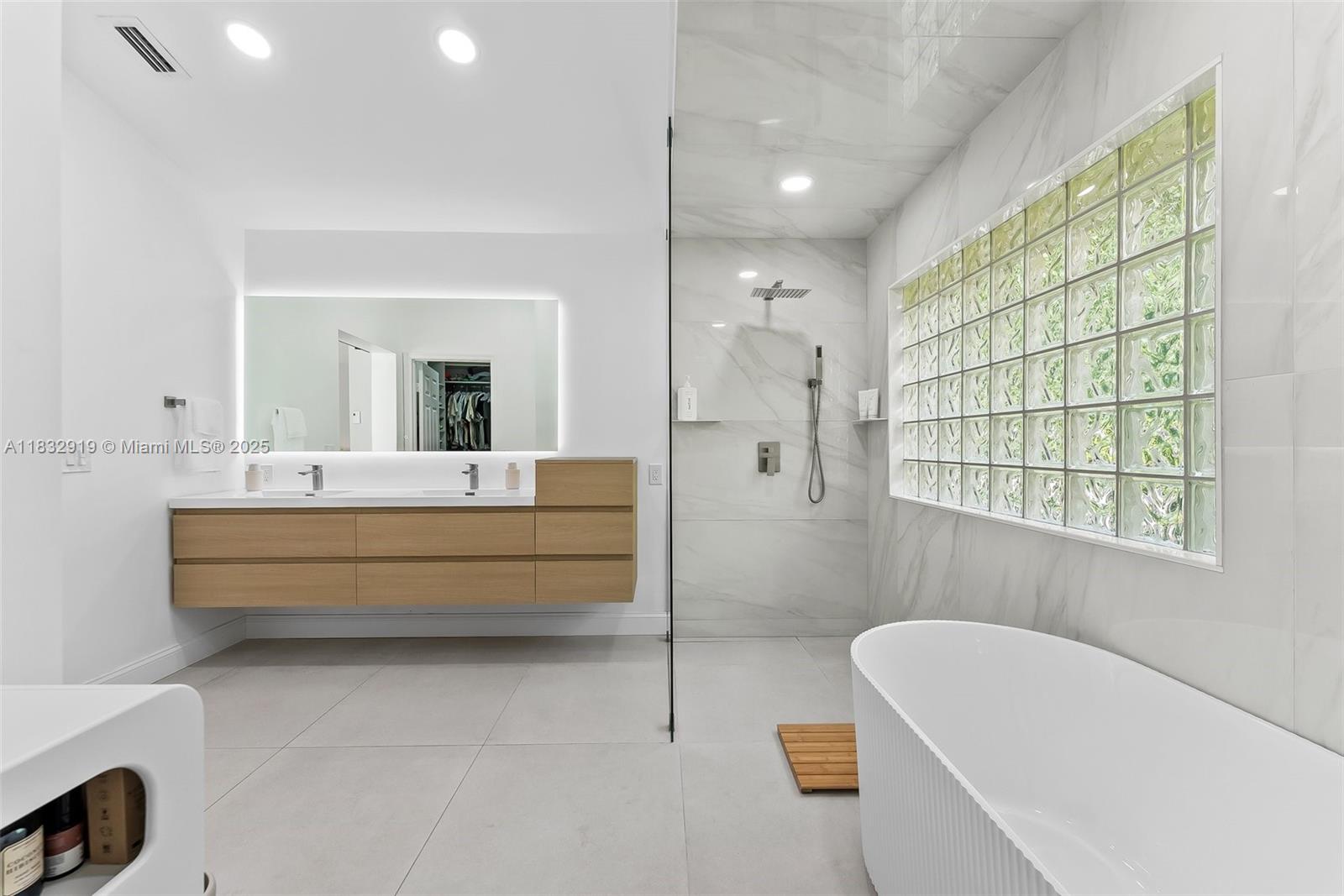 17723 Tiffany Trace Drive Boca Raton, FL 33487 - Photo 36 of 44 a bathroom with a tub a double vanity sink and a large mirror