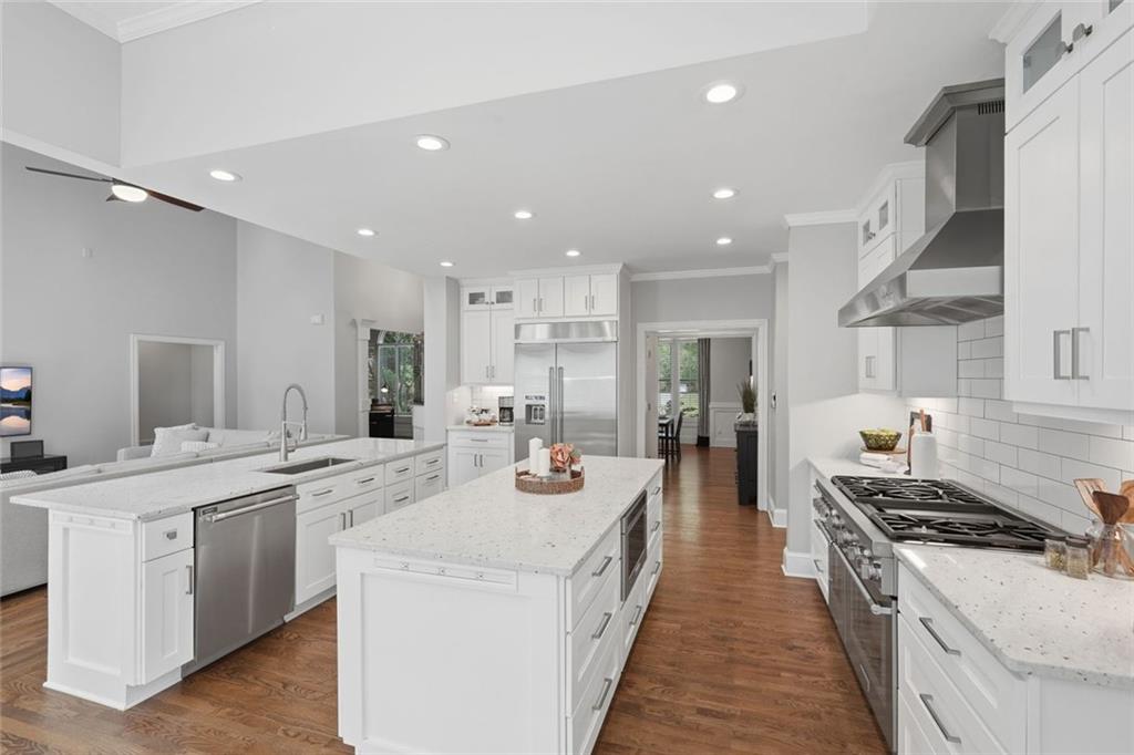 215 Bayfield Court Milton, GA 30004 - Photo 11 of 62 a large kitchen with stainless steel appliances a stove a sink dishwasher and a dining table with wooden floor
