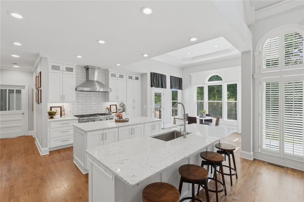 215 Bayfield Court Milton, GA 30004 - Photo 10 of 62 a kitchen with stainless steel appliances granite countertop a stove a sink a microwave a dining table and chairs with wooden floor