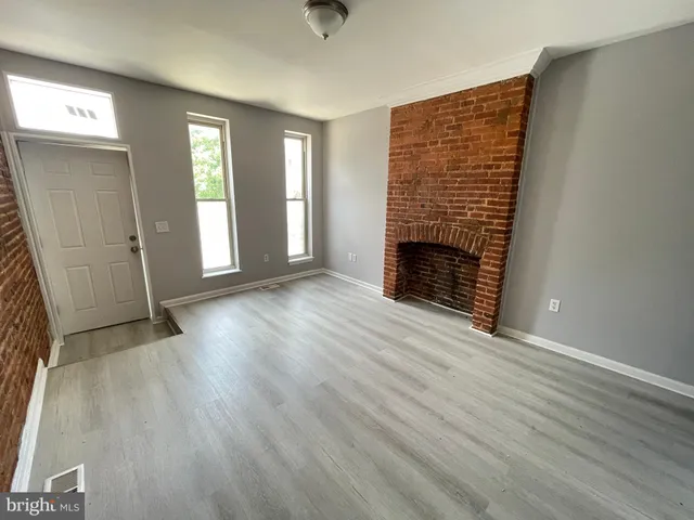 an empty room with windows and fireplace