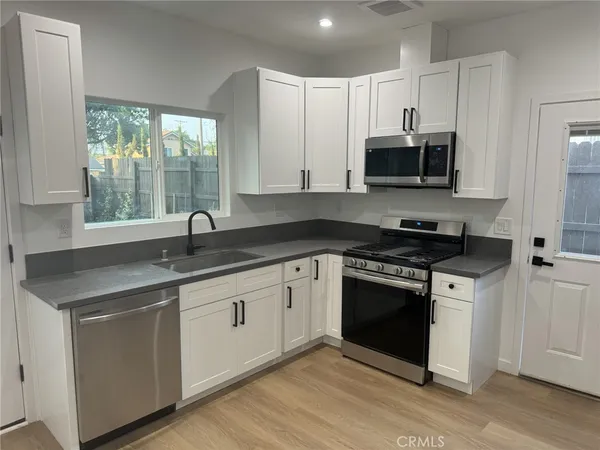 a kitchen with stainless steel appliances granite countertop a sink a stove and a microwave