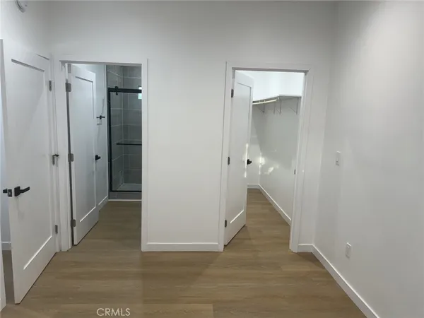 a view of a hallway with wooden floor and closet area