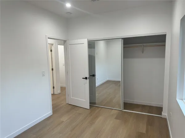 an empty room with wooden floor and closet area