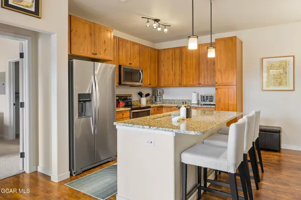 a kitchen with stainless steel appliances granite countertop a refrigerator a sink a stove a dining table and chairs