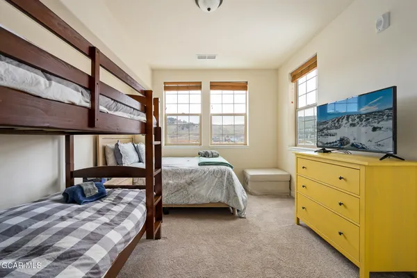 a bedroom with a bed and large windows