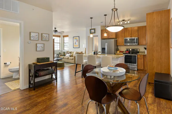 a living room with stainless steel appliances furniture a dining table and chairs