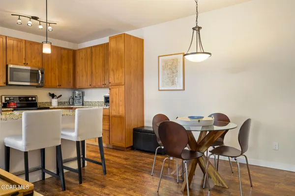 a kitchen with stainless steel appliances granite countertop a dining table chairs and white cabinets