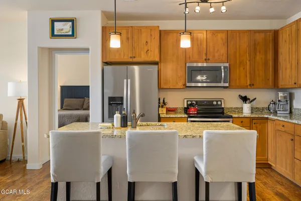 a kitchen with stainless steel appliances granite countertop a sink a microwave refrigerator and chairs