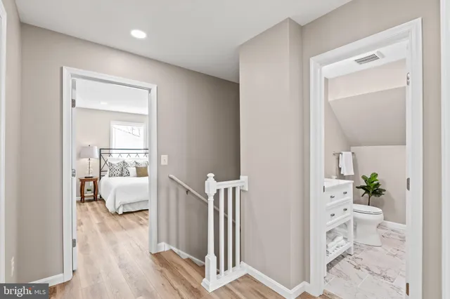a view of a hallway with wooden floor and a bathroom