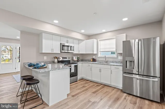 a kitchen with a sink a refrigerator and wooden floor