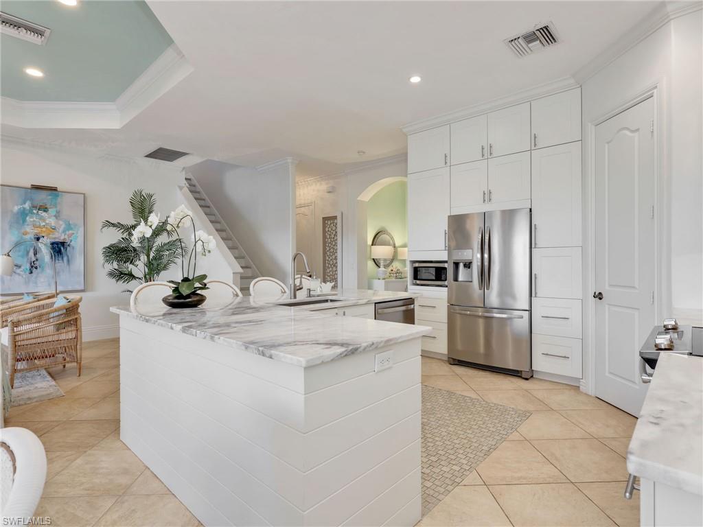 1365 Serrano Circle Naples, FL 34105 - Photo 12 of 46 Kitchen featuring ornamental molding, stainless steel appliances, arched walkways, recessed lighting, and white cabinetry