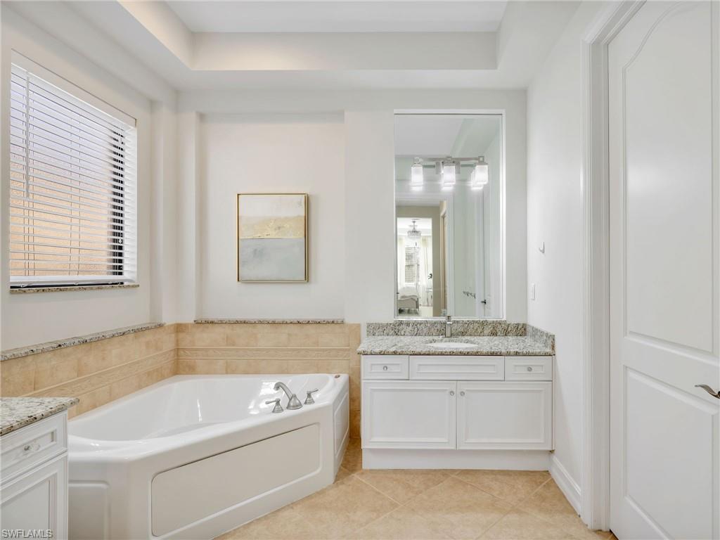 1365 Serrano Circle Naples, FL 34105 - Photo 30 of 46 Full bathroom with vanity, a bath, light tile patterned flooring, and a tray ceiling