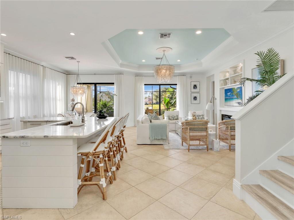 1365 Serrano Circle Naples, FL 34105 - Photo 8 of 46 Kitchen with light stone counters, a tray ceiling, a chandelier, decorative light fixtures, and ornamental molding