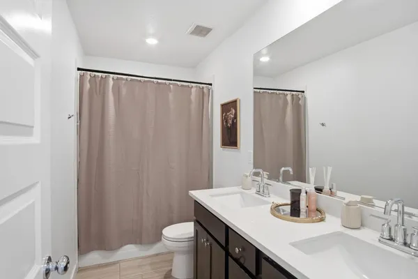 a bathroom with a double vanity sink toilet and a mirror