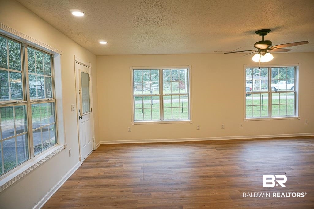 4734 Kirkwell Drive Mobile, AL 36619 - Photo 4 of 18 Spare room with ceiling fan, a wealth of natural light, dark hardwood / wood-style flooring, and a textured ceiling