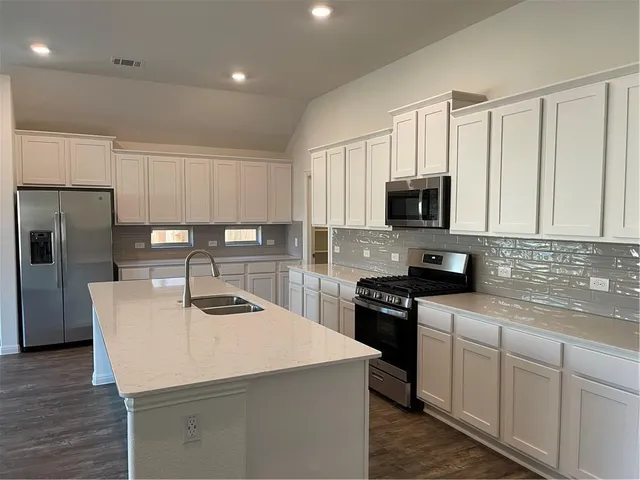 a kitchen with appliances a sink and cabinets