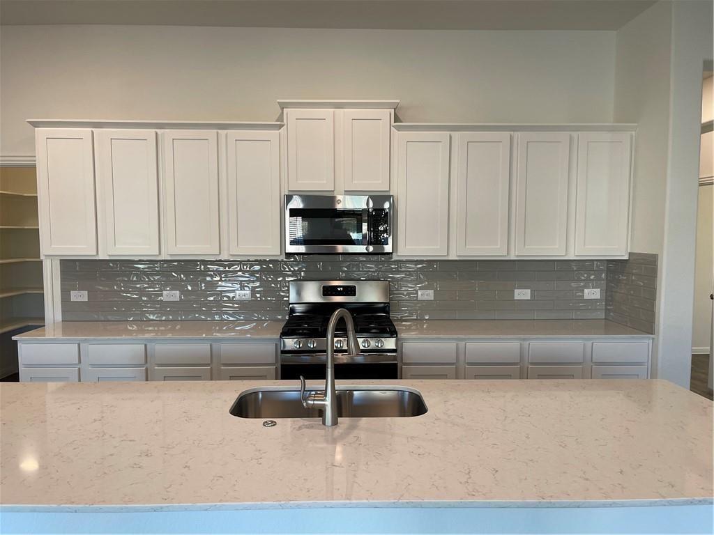 208 Baralo Street Leander, TX 78641 - Photo 7 of 23 a kitchen with a sink a stove and cabinets