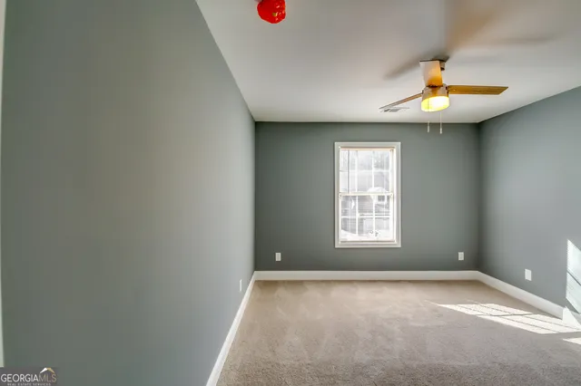 an empty room with a window and a ceiling fan