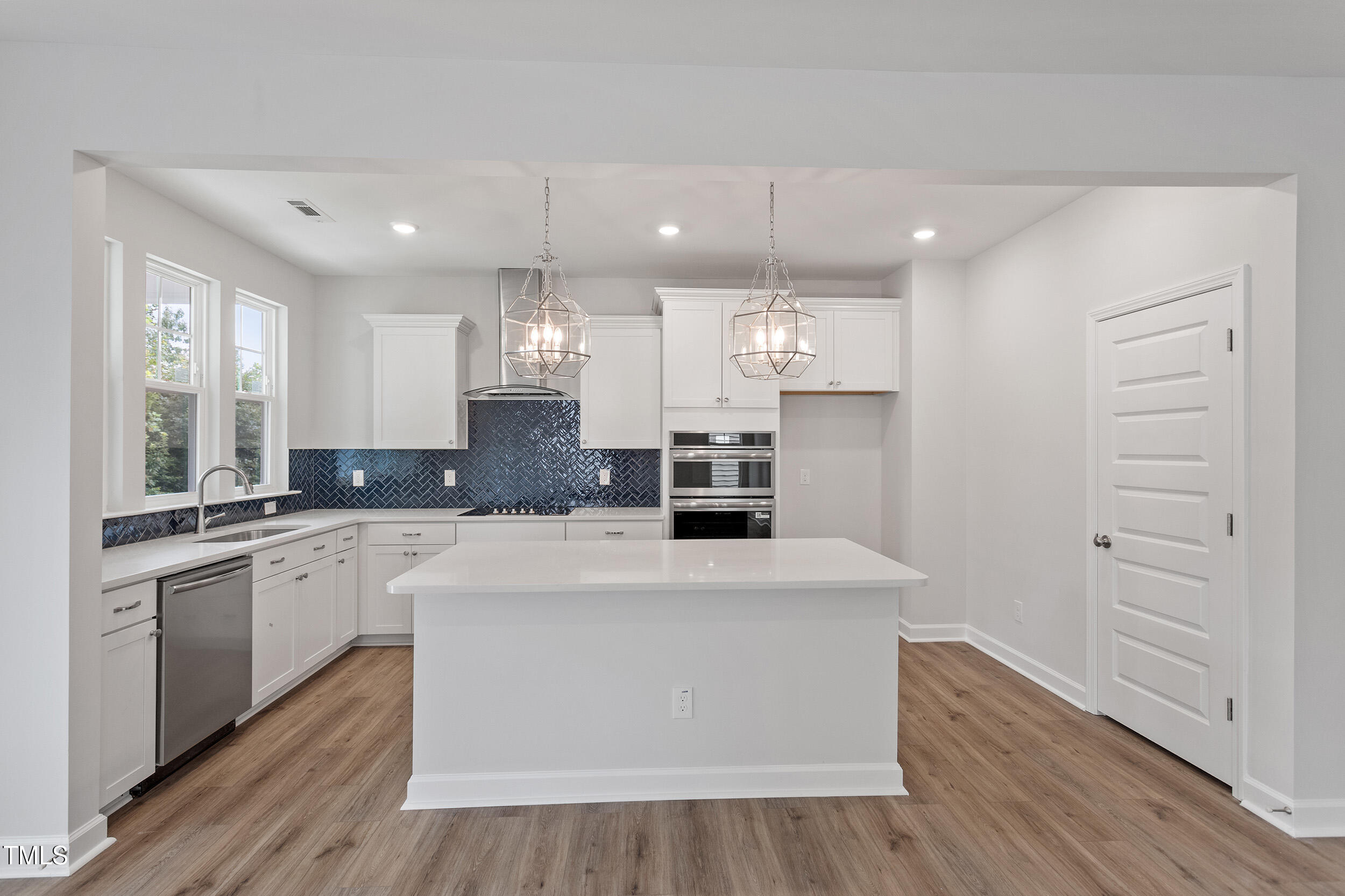 239 Meadowbark Bend, Unit 27 Garner, NC 27529 - Photo 10 of 36 a large kitchen with stainless steel appliances kitchen island a large counter top and white cabinets with wooden floor