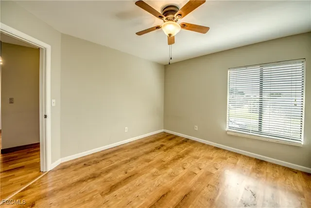 an empty room with a window and a ceiling fan