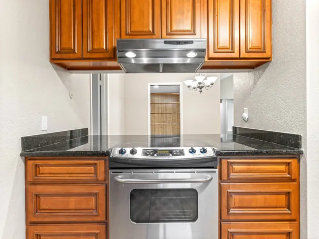 a kitchen with granite countertop a coffee maker on granite counter tops and white cabinets