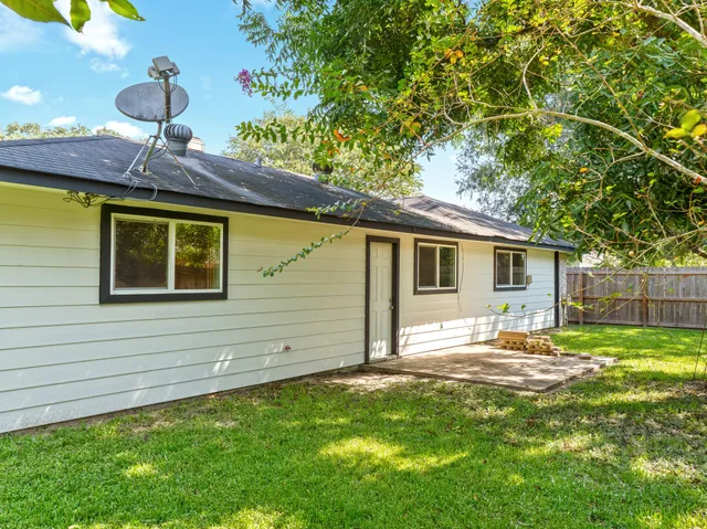 a backyard of a house with plants and a large tree