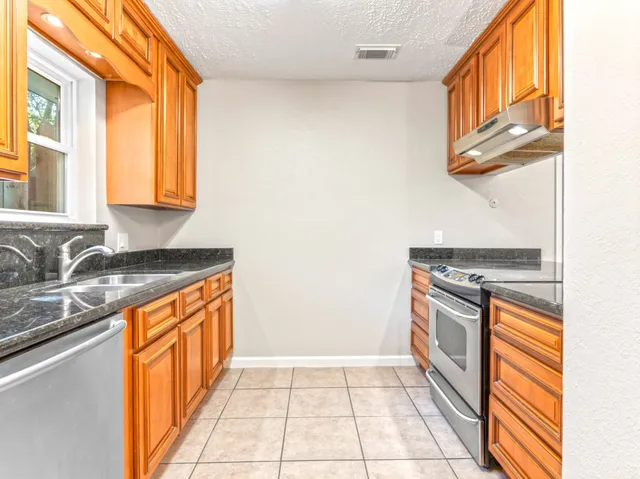 a view of a kitchen with granite countertop a sink and a stove top oven