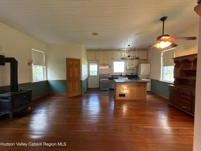 a kitchen with a refrigerator and a view of living room