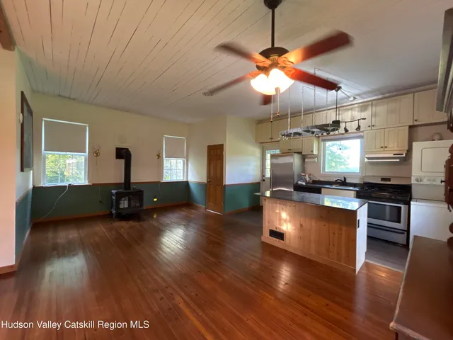 a kitchen with stainless steel appliances granite countertop a refrigerator a sink dishwasher a stove and a dining table with wooden floor