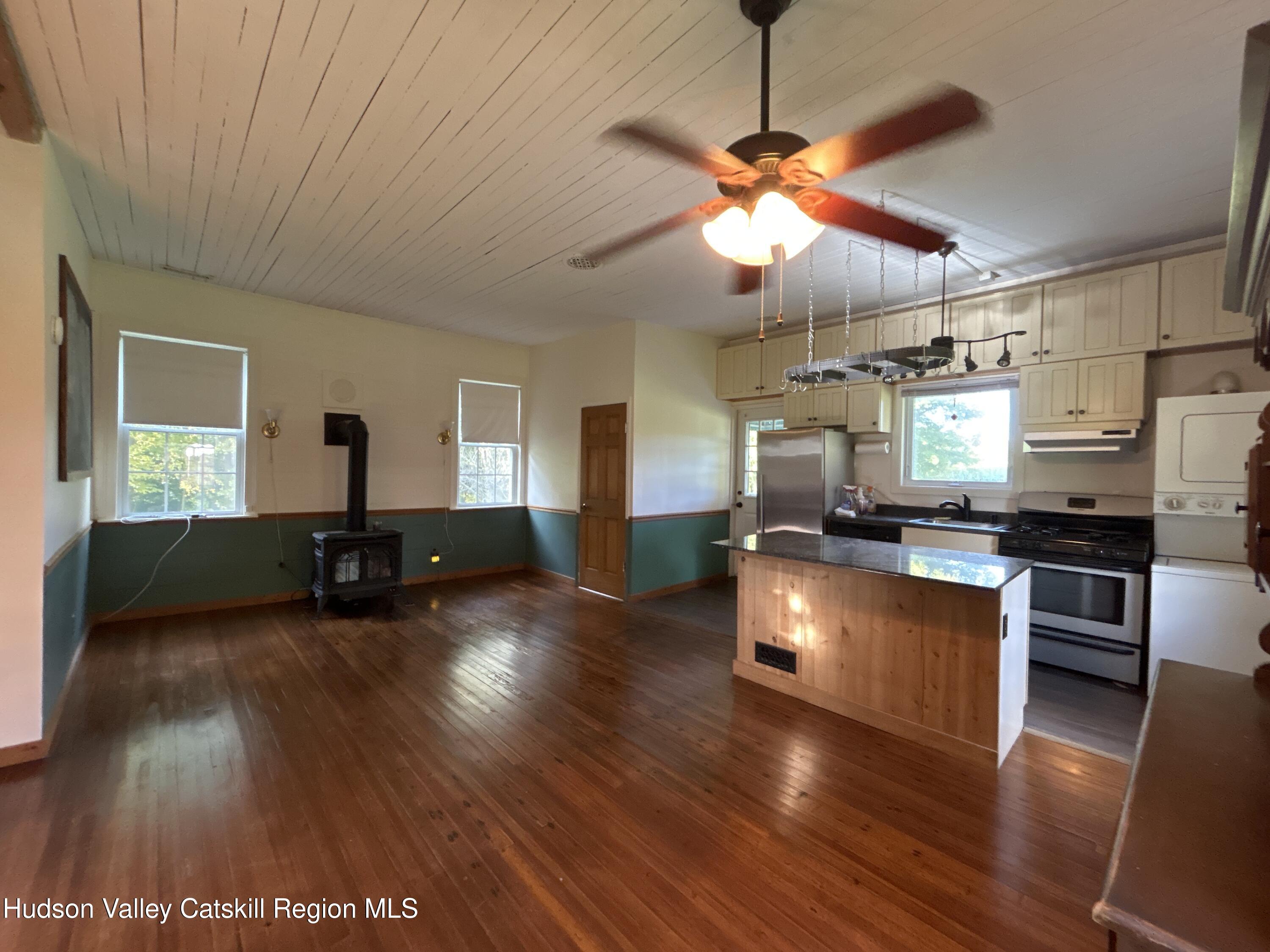 135 Rudd Pond Road Millerton, NY 12546 - Photo 4 of 10 a kitchen with stainless steel appliances granite countertop a refrigerator a sink dishwasher a stove and a dining table with wooden floor