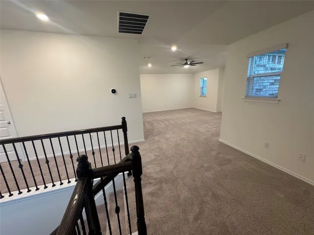 an empty room with windows and ceiling fan