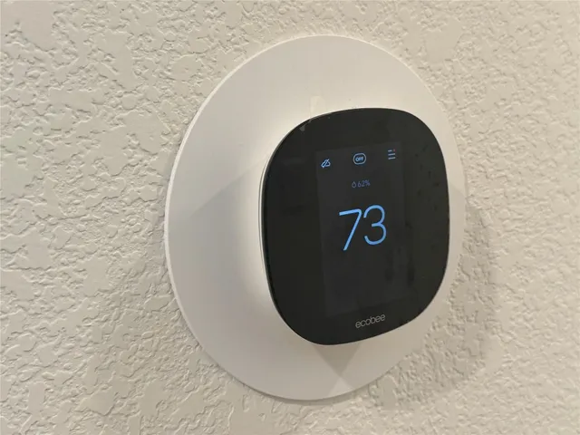 an empty room with wooden floor ceiling fan and kitchen view