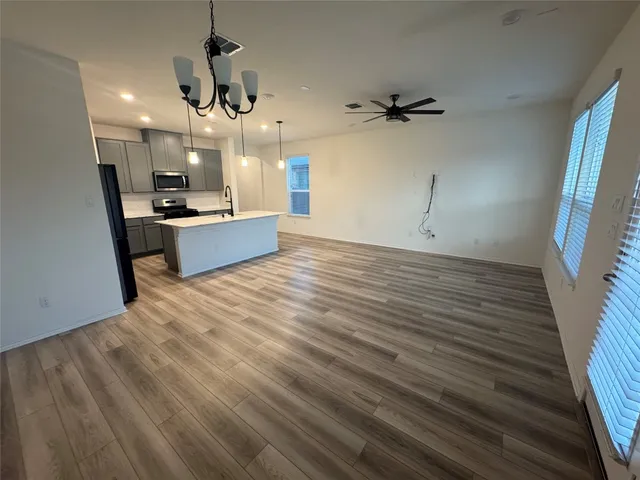 a large kitchen with kitchen island a sink dishwasher a refrigerator and wooden floor