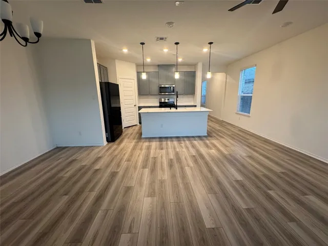 a view of an empty room with window and wooden floor