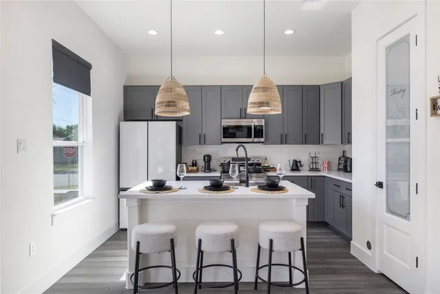 a kitchen with stainless steel appliances a table a sink cabinets and wooden floor